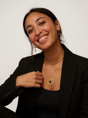 Dame souriante en tenue professionnelle, symbolisant le soin personnalisé et l'expertise à l'Atelier de Naila, Alfortville.